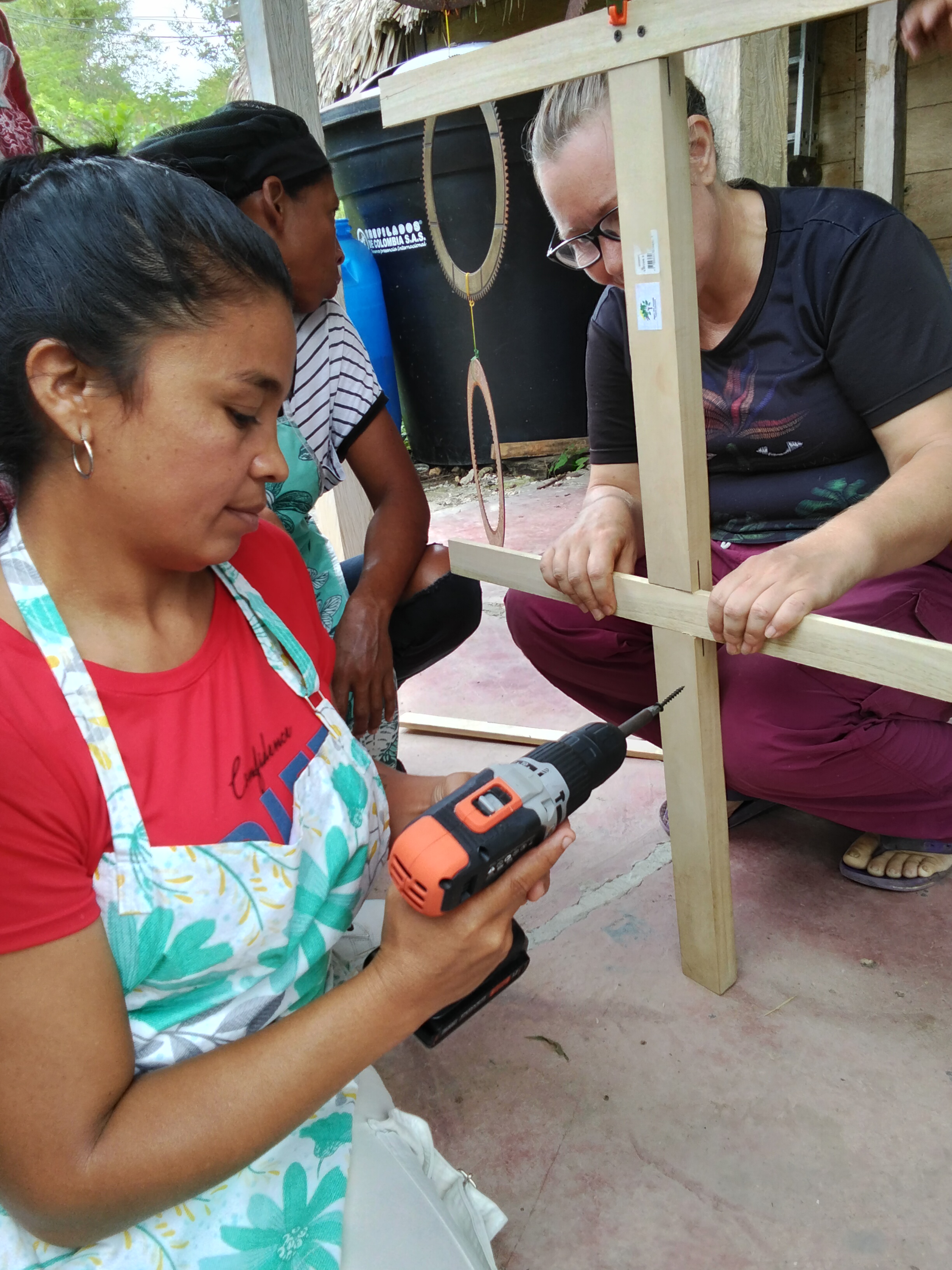 Participantes armando la estructura de madera con un taladro.