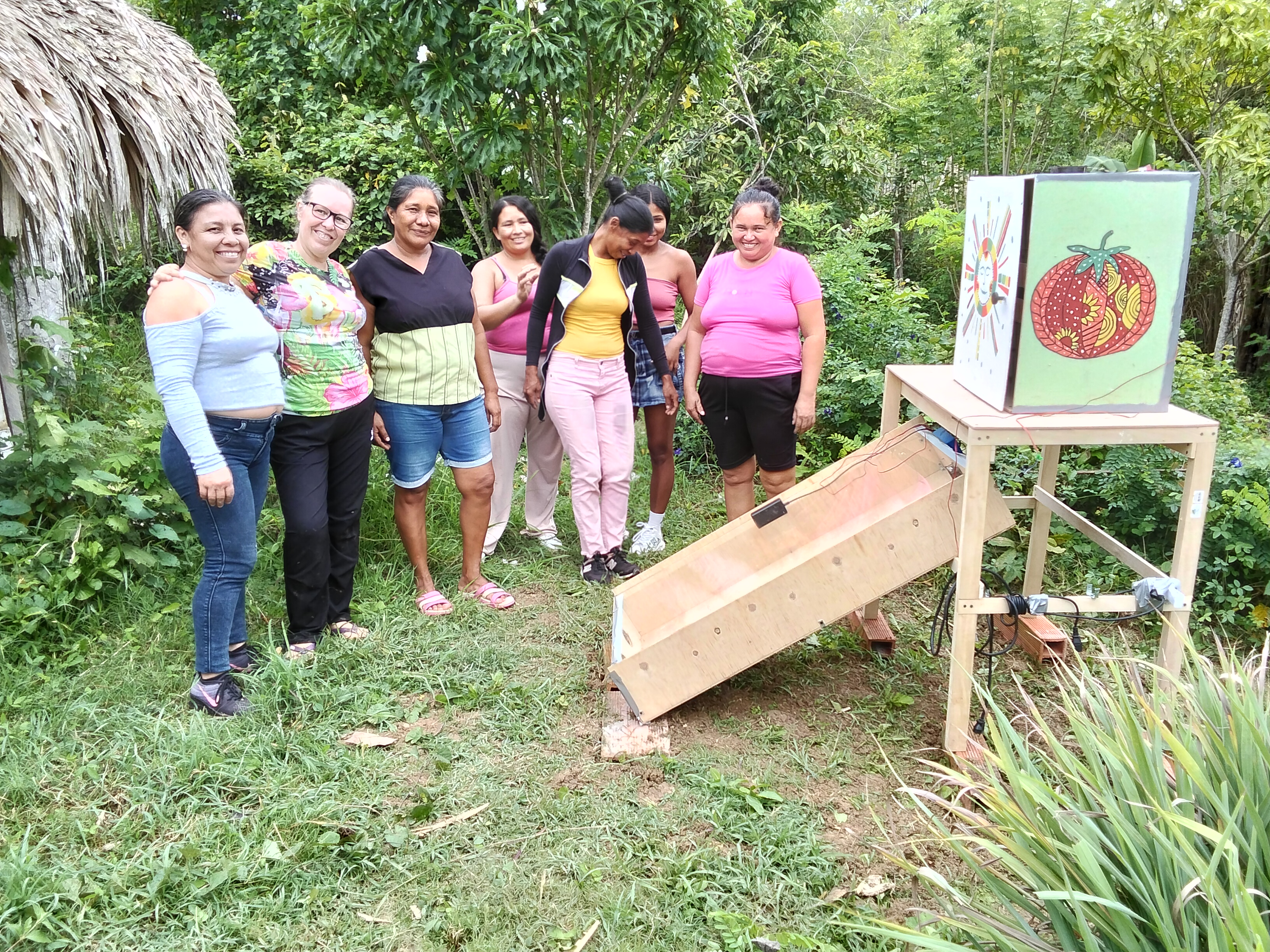 Grupo junto a la deshidratadora solar terminada en un espacio exterior comunitario.
