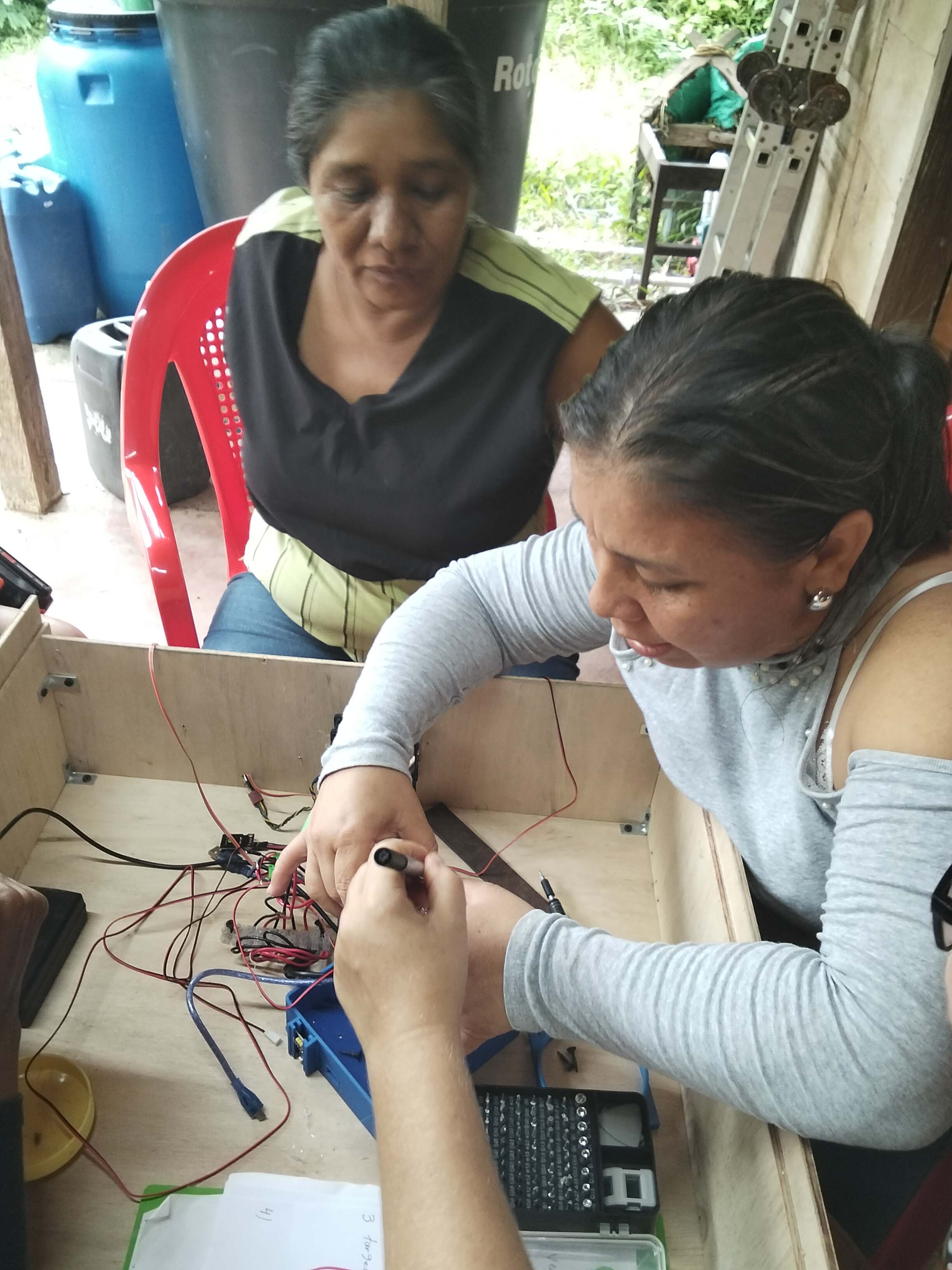 Participantes conectando cables y piezas en el interior de la deshidratadora solar.